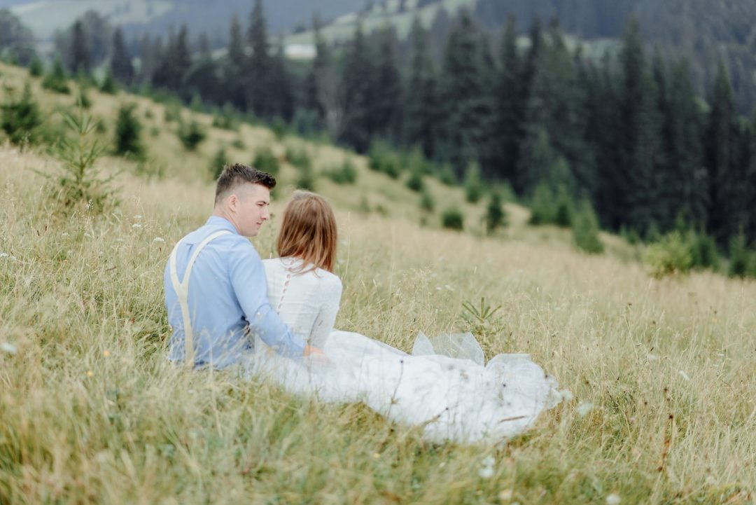 Bride and groom seated in meadow