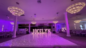 Elegant event space with purple lighting, chandeliers, and illuminated letters spelling "JOCELYN
